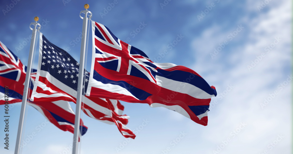 Hawaii state flag waving with the national flag of the United States of America on a clear day
