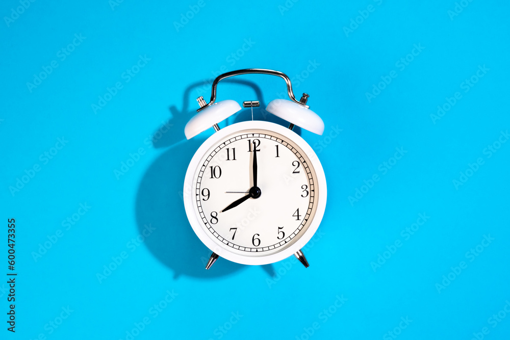 White alarm clock on a blue background isolated, top view. White alarm clock on a blue background isolated, top view.