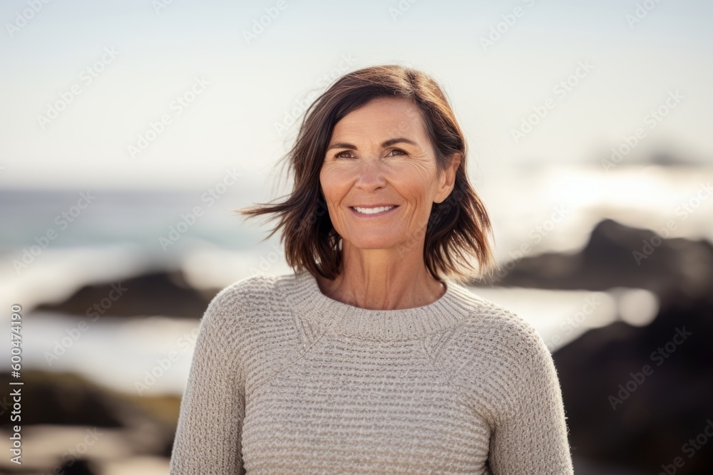 Portrait of smiling mature woman standing on beach at the day time