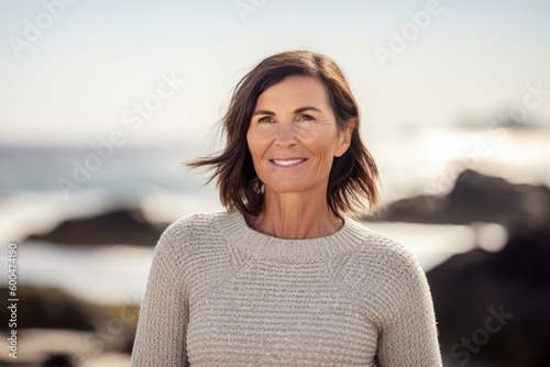Portrait of smiling mature woman standing on beach at the day time © Robert MEYNER