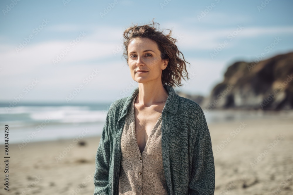 Front view of a beautiful young woman with curly hair standing on the beach by the sea Front view of a beautiful young woman with curly hair standing on the beach by the sea