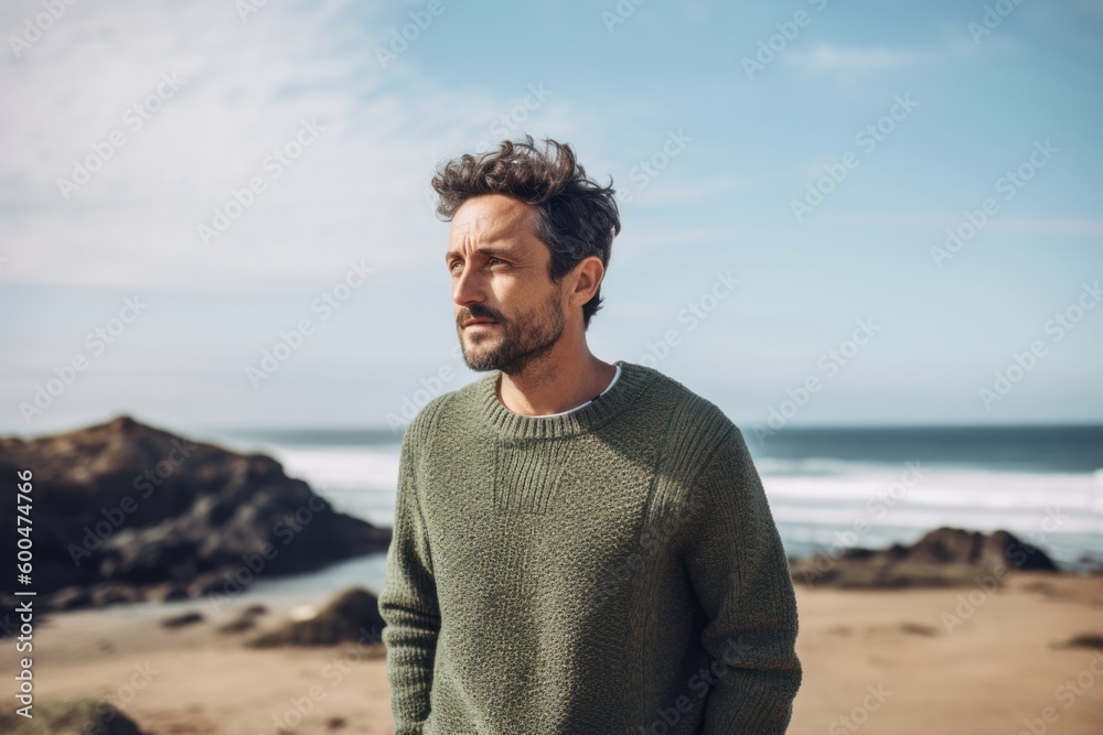 Portrait of a handsome man standing on the beach and looking away