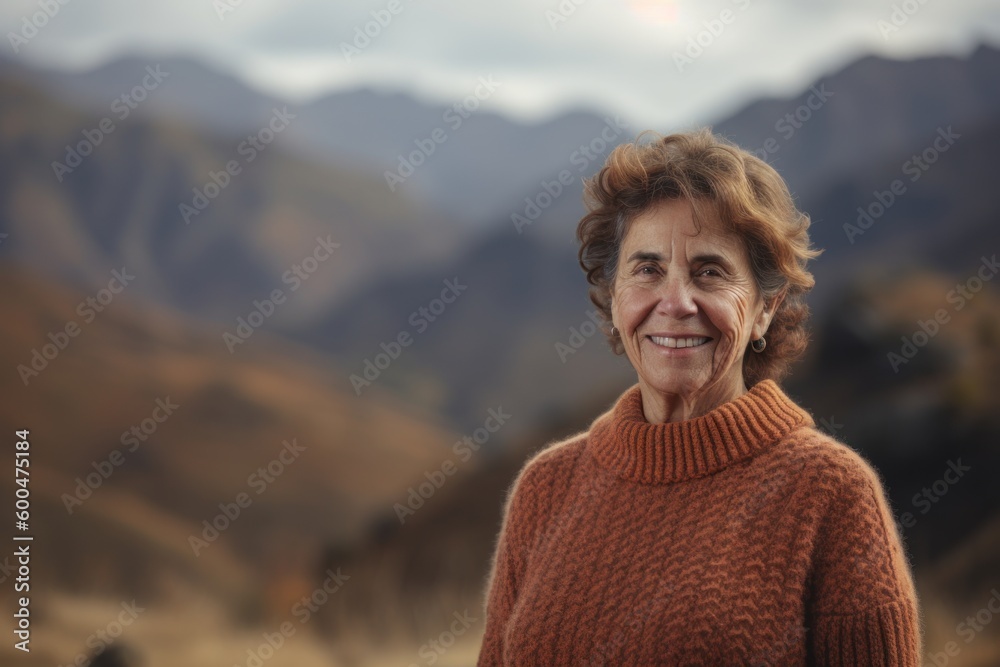 Naklejka premium Portrait of a smiling senior woman in a sweater in the mountains