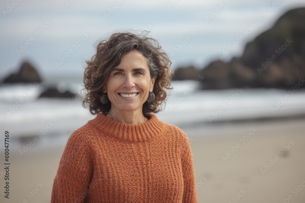 Portrait of smiling mature woman standing on beach with ocean in background Portrait of smiling mature woman standing on beach with ocean in background