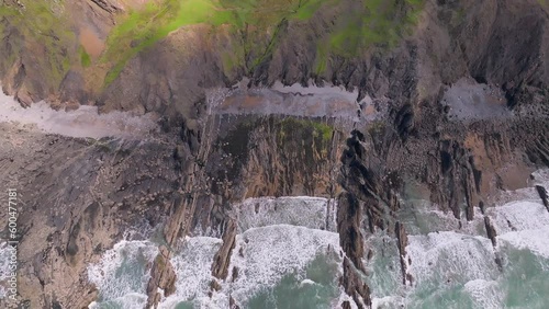 Aerial tracking  shot of rocky coastline with waves coming in towards the sea cliffs.