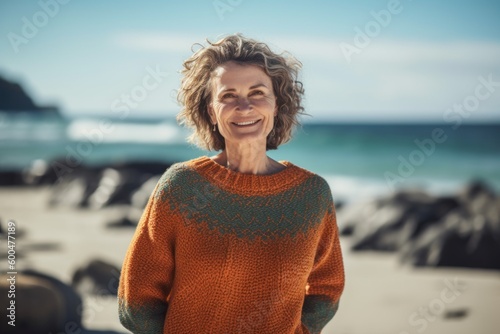 Portrait of smiling senior woman standing on beach and looking at camera © Robert MEYNER