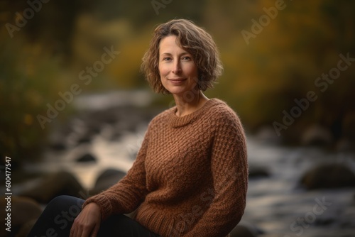 Portrait of a middle-aged woman in a knitted sweater on the background of a mountain river.