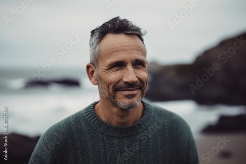 Portrait of handsome mature man smiling at camera while standing on beach