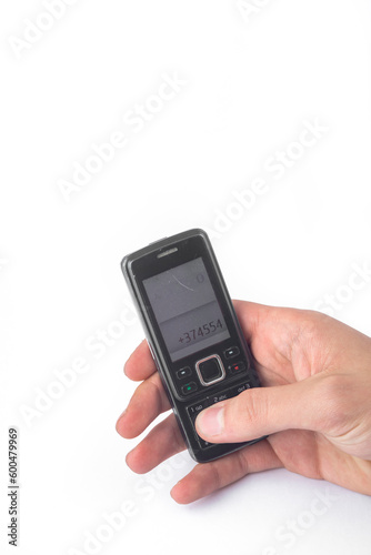 Old push-button cell phone in hand isolated on white background, clipping path included.
