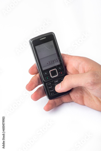Old push-button cell phone in hand isolated on white background, clipping path included.