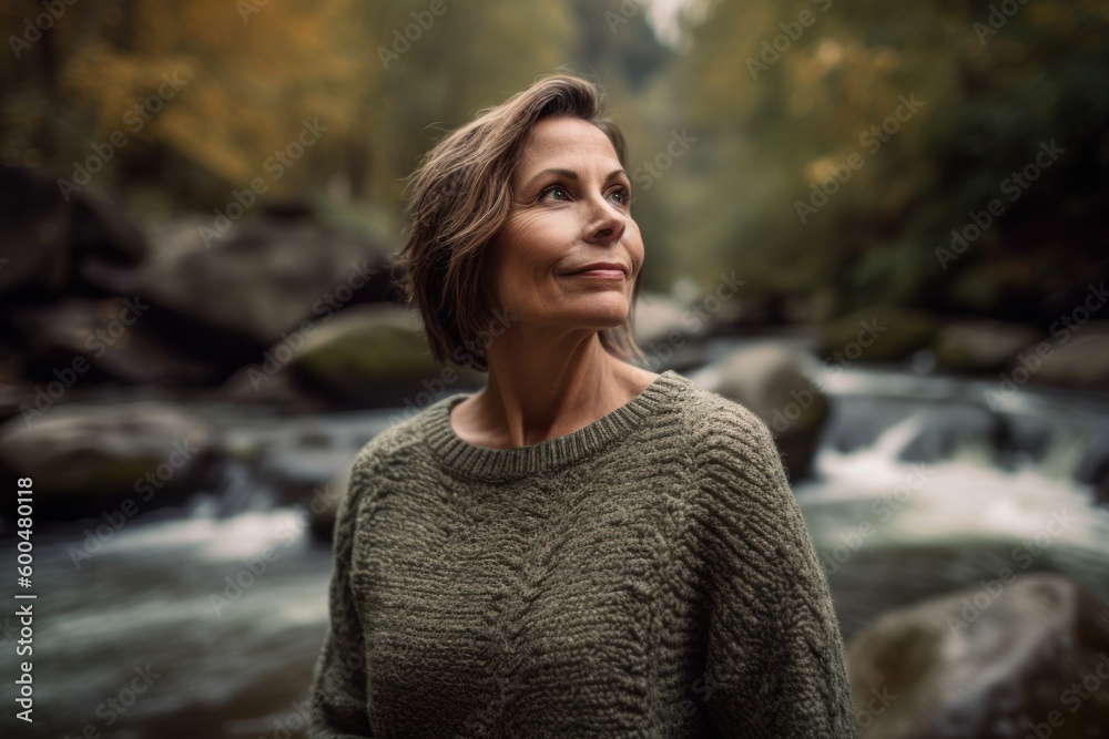 Portrait of a middle-aged woman in a knitted sweater on the background of a waterfall Portrait of a middle-aged woman in a knitted sweater on the background of a waterfall