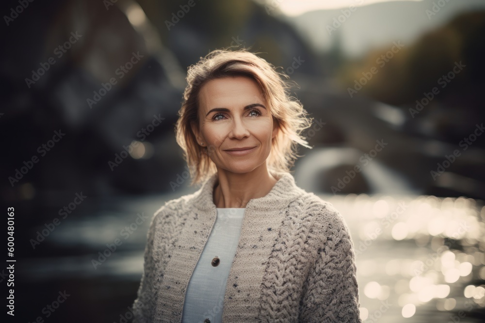 Portrait of a beautiful middle-aged woman in a knitted sweater on the background of the river Portrait of a beautiful middle-aged woman in a knitted sweater on the background of the river