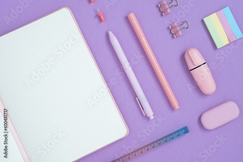 Empty notebook page for your text with pastel pink school and office stationery on violet background. Flatly.