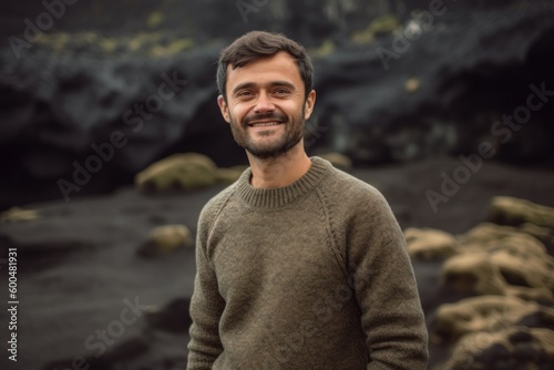 Portrait of a handsome young man smiling at the camera while standing in front of a volcanic landscape