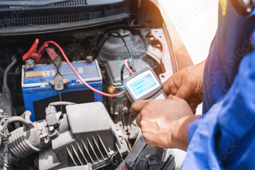 A multimeter voltmeter is used by auto mechanics to measure the voltage of a car battery. © chartphoto