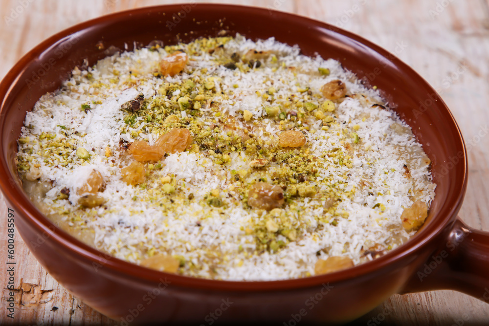 Rice Mahalabia topping with nuts powder served in dish isolated on table top view of arabic dessert Rice Mahalabia topping with nuts powder served in dish isolated on table top view of arabic dessert