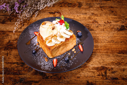honey toast bread with topping strawberry ,banana , cheese and vanilla ice cream on wooden table,