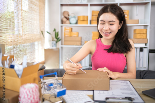 Woman is writing down the customer's details and addresses on the notebook or post box in order to prepare for shipping according to the information, Packing box, Sell online, Freelance working.