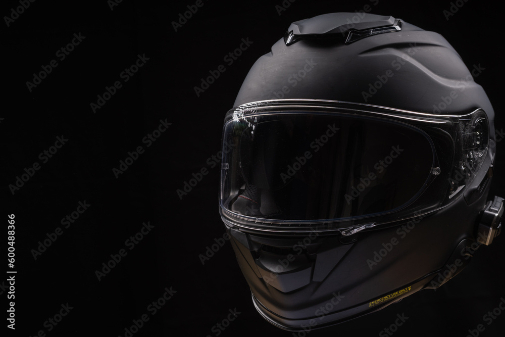 Black motorcycle helmet on dark background, space for text 