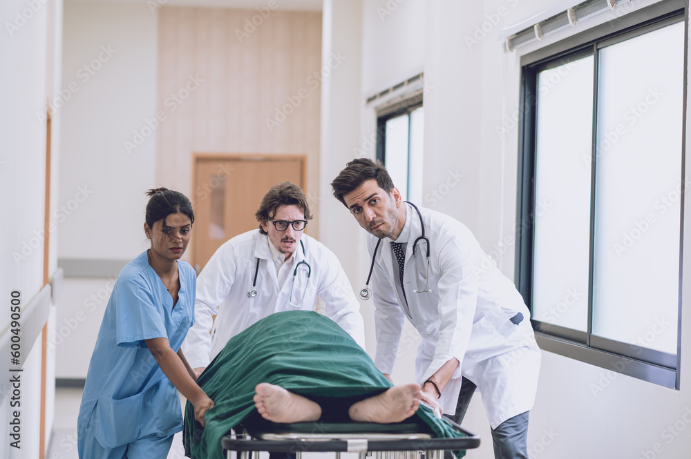 Obraz premium Doctors, Nurses, and Paramedics pushing stretcher gurney bed with seriously injured patient towards the operating room. Professional Staff Saving Lives. Health care Concept.
