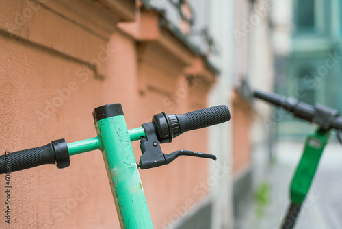 Close-up on the handlebars of electric scooters abandoned in the center of the old city.