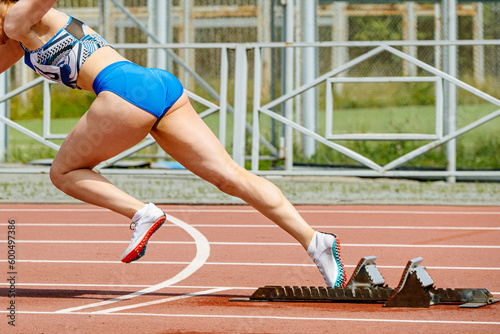 close-up female sprinter start running from starting blocks in summer athletics championships