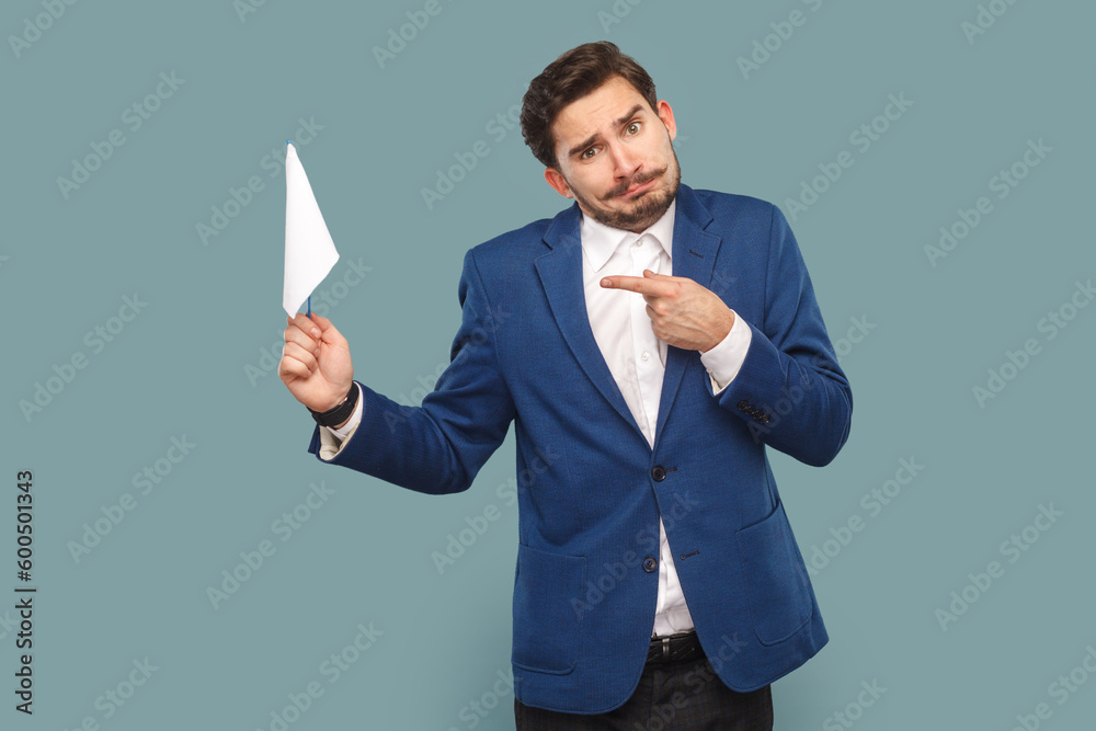 Portrait of stressed man with mustache standing and pointing at white flag, looking at camera with frowning face, wearing white shirt and jacket. Indoor studio shot isolated on light blue background. Portrait of stressed man with mustache standing and pointing at white flag, looking at camera with frowning face, wearing white shirt and jacket. Indoor studio shot isolated on light blue background.