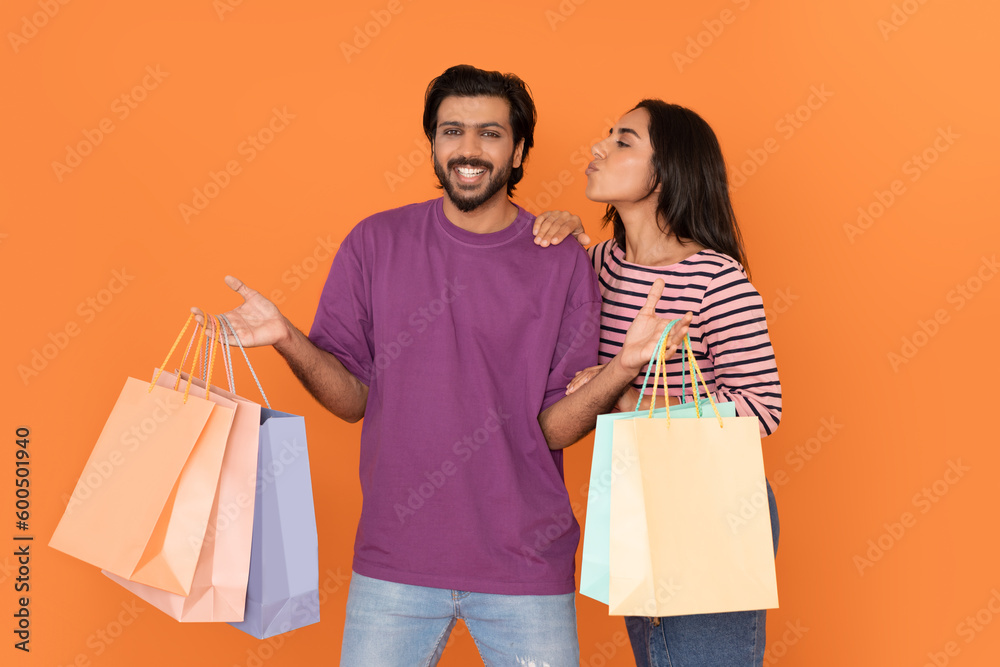 Beautiful young indian couple customers shopping together on orange Beautiful young indian couple customers shopping together on orange