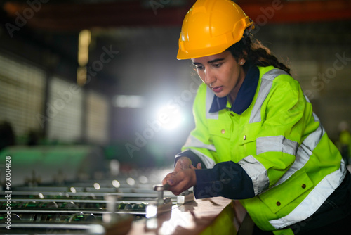 Factory engineer Brazilian woman checking and reparing mahine at heavy factory.Worker works at heavy machine at industry factory. with machinery equipment plant technology. photo