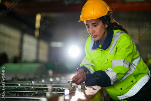 Factory engineer Brazilian woman checking and reparing mahine at heavy factory.Worker works at heavy machine at industry factory. with machinery equipment plant technology. photo