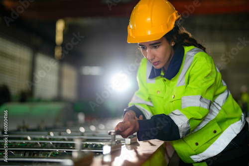 Factory engineer Brazilian woman checking and reparing mahine at heavy factory.Worker works at heavy machine at industry factory. with machinery equipment plant technology. photo