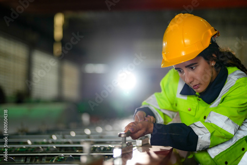 Factory engineer Brazilian woman checking and reparing mahine at heavy factory.Worker works at heavy machine at industry factory. with machinery equipment plant technology. photo