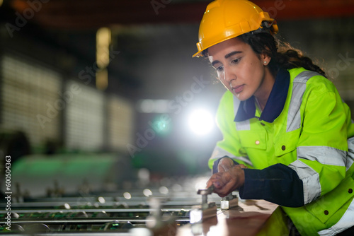 Factory engineer Brazilian woman checking and reparing mahine at heavy factory.Worker works at heavy machine at industry factory. with machinery equipment plant technology. photo