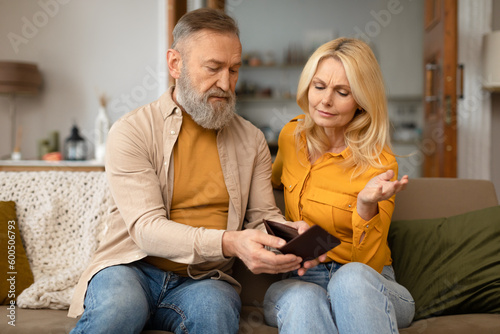 Unhappy Senior Couple Looking At Empty Wallet Sitting At Home