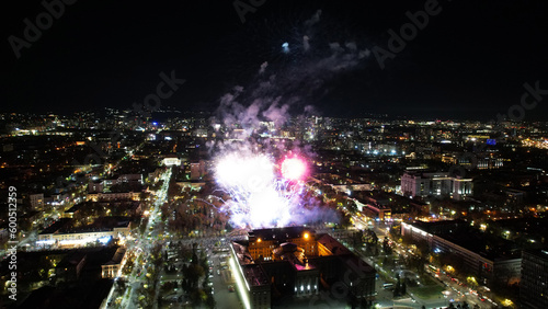 Huge bright flashes from fireworks in the city center. Aerial view from a drone on the night city of Almaty, colored lights and lanterns. People are resting. Cars are coming. A holiday in the city