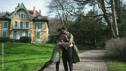 Happy couple standing outside at park going for a stroll. Affectionate boyfriend pushing and teasing girlfriend away and embracing her back