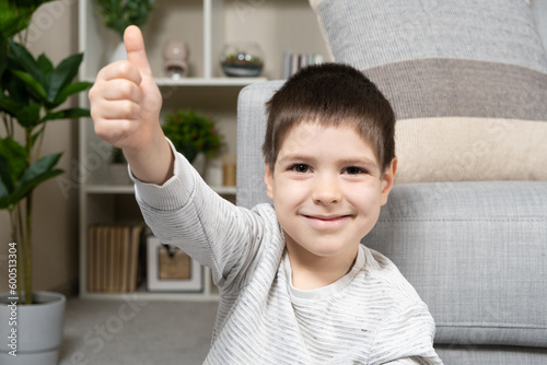 A 5-year-old boy shows his fingers up and smiles