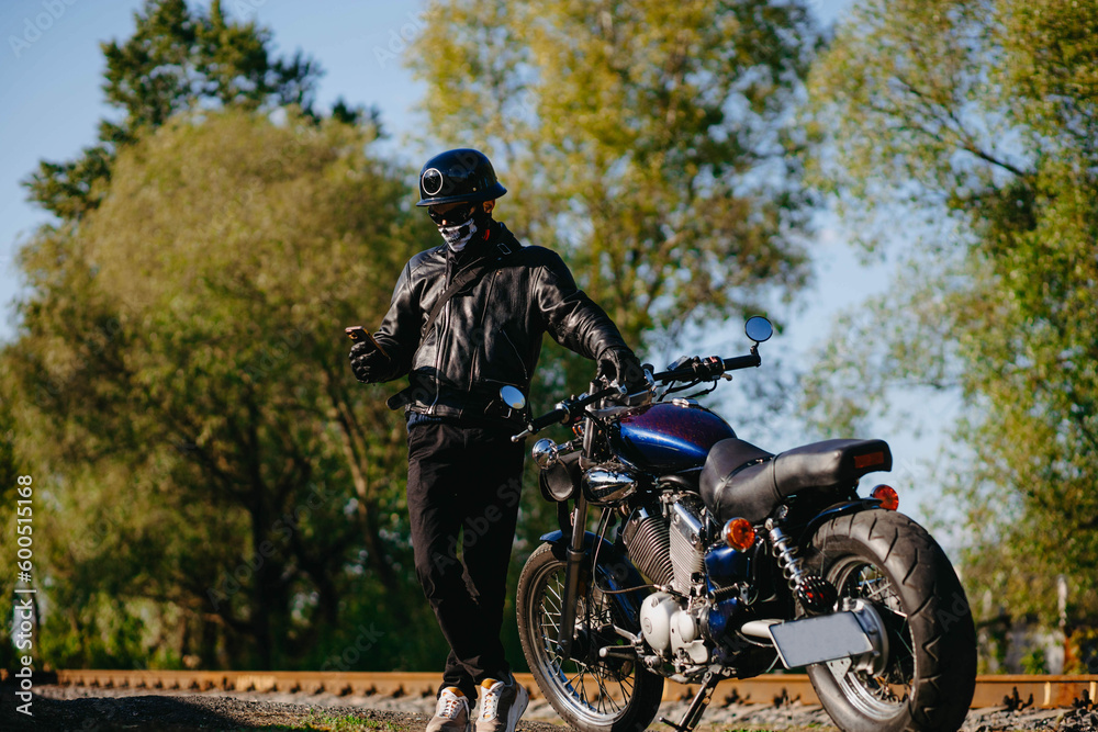 stylish male motorcyclist biker in mask and helmet with custom handmade motorcycle cruiser chopper. Stylish retro motorcycle stylish male motorcyclist biker in mask and helmet with custom handmade motorcycle cruiser chopper. Stylish retro motorcycle