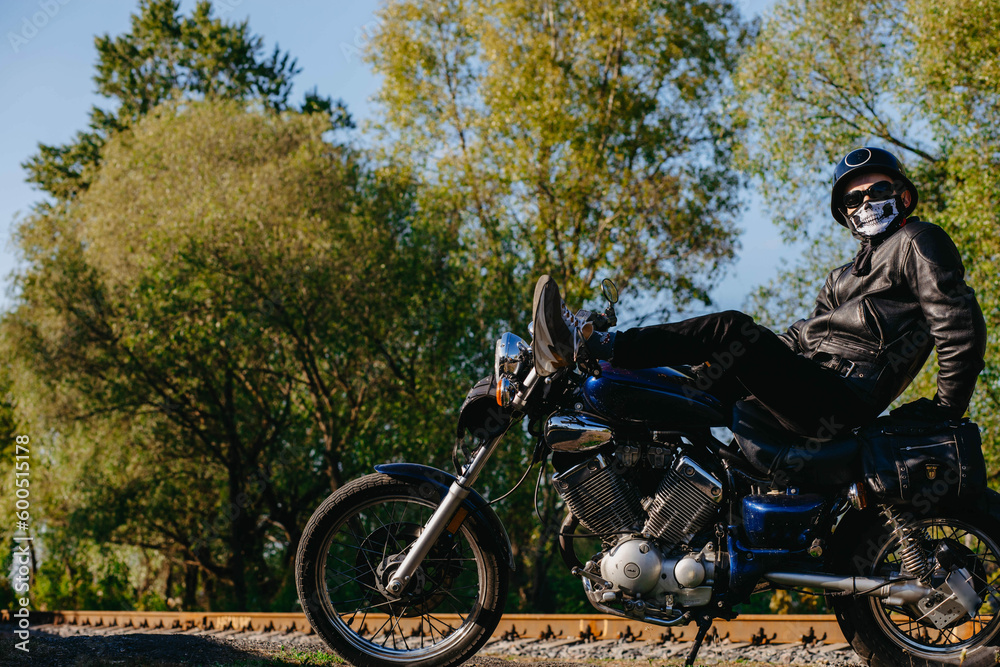 stylish male motorcyclist biker in mask and helmet with custom handmade motorcycle cruiser chopper. Stylish retro motorcycle stylish male motorcyclist biker in mask and helmet with custom handmade motorcycle cruiser chopper. Stylish retro motorcycle