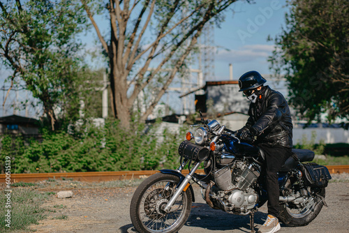 stylish male motorcyclist biker in mask and helmet with custom handmade motorcycle cruiser chopper. Stylish retro motorcycle