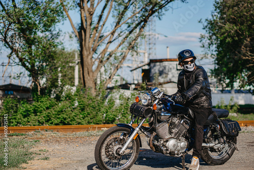 Fototapeta Naklejka Na Ścianę i Meble -  stylish male motorcyclist biker in mask and helmet with custom handmade motorcycle cruiser chopper. Stylish retro motorcycle