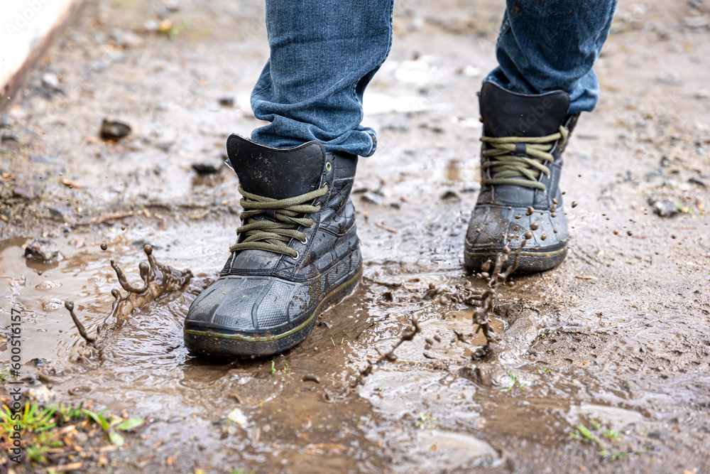 A man in jeans and boots walks through the swamp in rainy weather. A man in jeans and boots walks through the swamp in rainy weather.