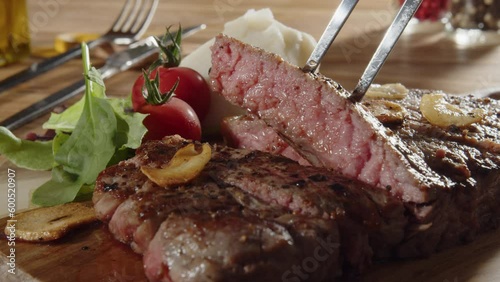 Lifting up a cut beefsteak on a wood board 01