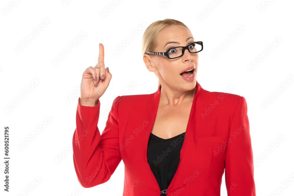 Middle aged surprised senior business woman in red jacket and glasses pointing up on white background Middle aged surprised senior business woman in red jacket and glasses pointing up on white background