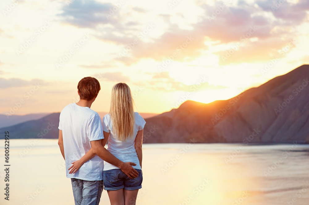 Honey moon on the sea shore. Romantic loving couple standing together on the beach enjoying sunset.