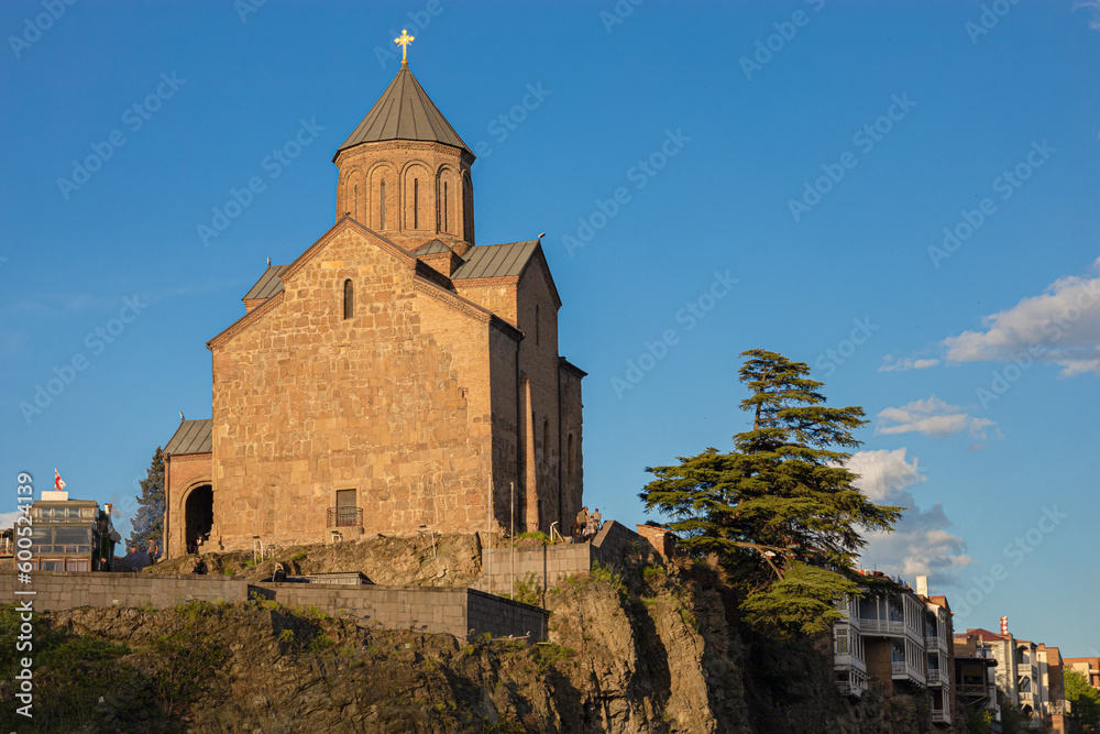 Metekhi Christian Orthodox church on a cliff next to the Kura river during the golden hour