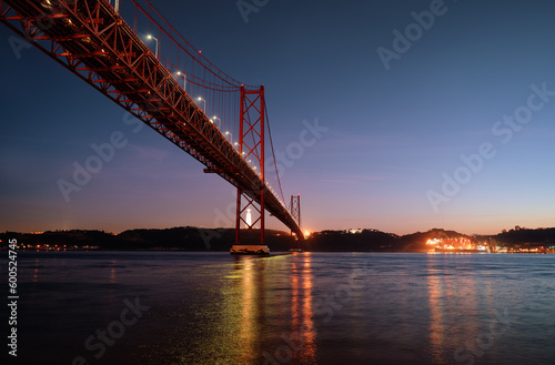 Beautiful landscape with suspension 25 April bridge over the Tagus river in Lisbon at night time, Portugal.