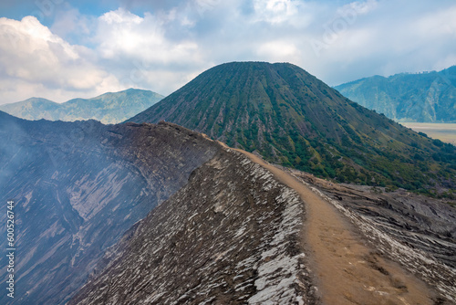 Hiking trail along the edge of Mount Bromo's crater with Mount Semeru, Mount Batok and the Sea of Sand (Segara Wedi) in the background, East, Java, Indonesia photo