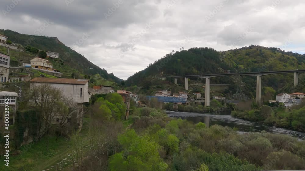 Traveling through the new Os Peares bridge where you can see the confluence of the Miño river and the Sil river and the blue metal railway bridge and the Peares viaduct where the N-120 circulates Traveling through the new Os Peares bridge where you can see the confluence of the Miño river and the Sil river and the blue metal railway bridge and the Peares viaduct where the N-120 circulates