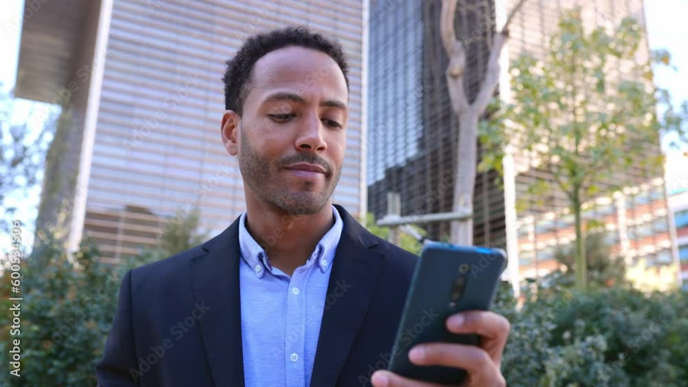Young attractive african american business man using mobile phone over modern building office background Young attractive african american business man using mobile phone over modern building office background